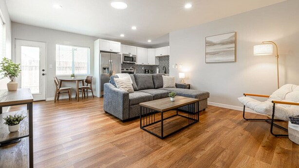 Un salon moderne avec un canapé gris, une table basse en bois et un coin repas comprenant une table et des chaises.