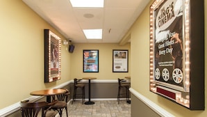 Un cinéma avec une affiche annonçant la projection quotidienne de films intéressants, un petit bar avec des tabourets et un sol carrelé.
