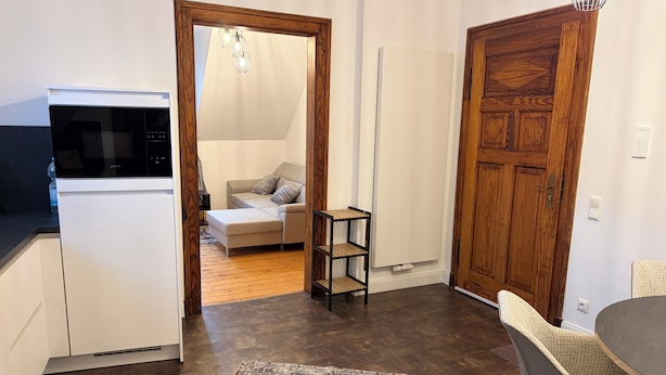 Un espace de vie compact comprenant un coin cuisine, un coin repas et un coin salon confortable agrémenté d’un tapis à motifs.
