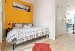 Une chambre à coucher avec un lit, une table de chevet, un tapis rouge et un tableau accroché au mur.
