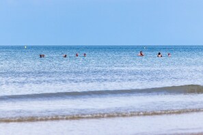 A beach with people swimming and a clear sky. - Ty Wawr: Spacious 3-Bedroom Holiday Home, Anglesey (Brynteg)