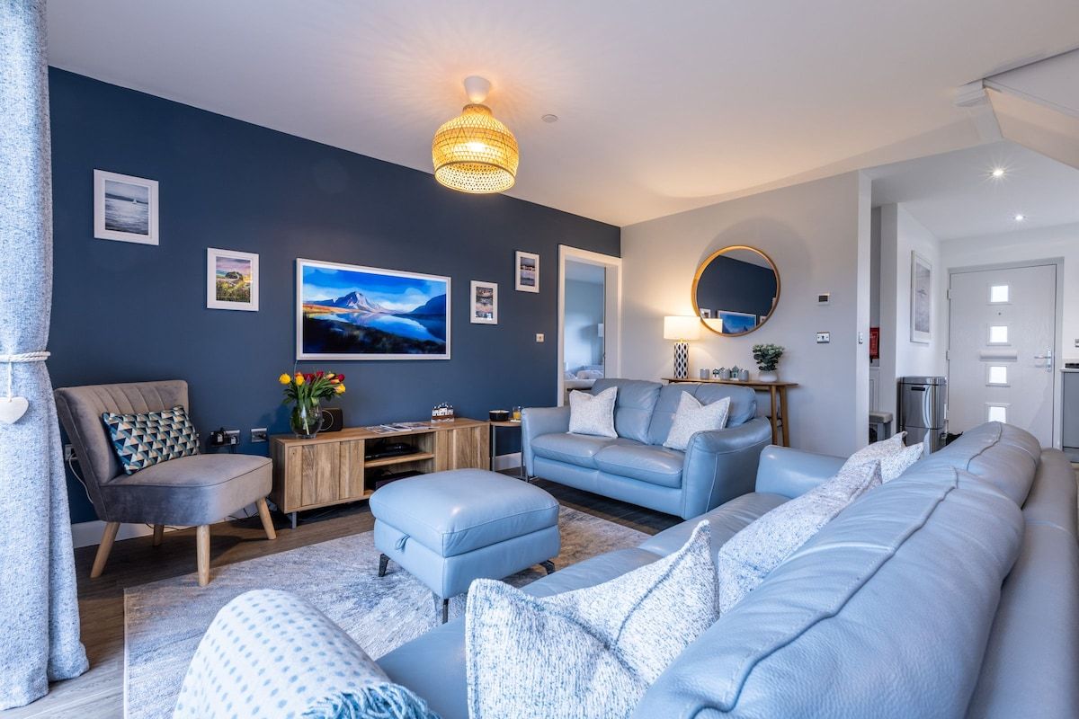 Ein modernes Wohnzimmer mit einer Sofagarnitur, einem Couchtisch, einem Beistelltisch und einer dekorativen Lampe.