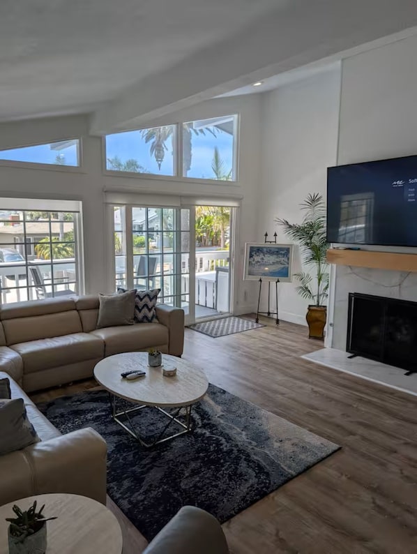 A spacious living room with a large sofa, a coffee table, and a fireplace. - DP Lantern District Townhouse STR-23-0105 (Dana Point)