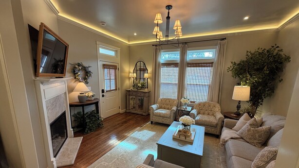 A living room with a fireplace, two armchairs, a sofa, a coffee table, and a chandelier. - Luxuriously Restored Early American Farmhouse (Cañon City)