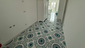 A hallway with patterned floor tiles, white walls, and a door leading to another room. - Large apartment Always strength Naples (Napoli)