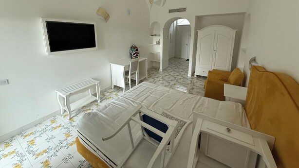 A bedroom with a bed, a desk, a chair, a wardrobe, and a television. - Large apartment Always strength Naples (Napoli)
