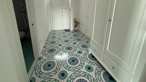 A hallway with patterned floor tiles, white doors, and a fire extinguisher. - Large apartment Always strength Naples (Napoli)