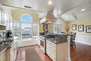 A kitchen with white cabinets, granite countertops, a built-in oven, and a large window. - Downtown! Above local businesses and walking distance to everything! (Harbor Springs)