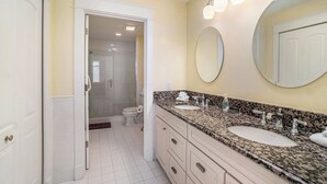 Un baño con tocador de doble lavabo, un espejo grande y una ducha a ras de suelo.