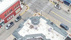 Vista aérea de un edificio con un techo octogonal distintivo, un estacionamiento y una calle con coches.