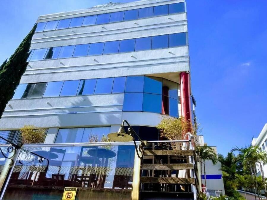 A modern building with multiple floors, large windows, and a red column.
