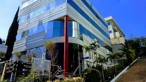 A modern building with a curved facade, large windows, and a red pillar. - Compacto Hotel Campinas (Campinas)
