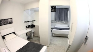 A hotel room with a bed, a desk, a chair, a small table, a mirror, and a window with curtains. - Compacto Hotel Campinas (Campinas)