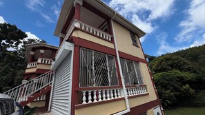 A multi-story building with a balcony, large windows, and a staircase. - Adorable 3-bedroom apartment with AC in Elms Hall Roseau. (Elms Hall, Roseau)