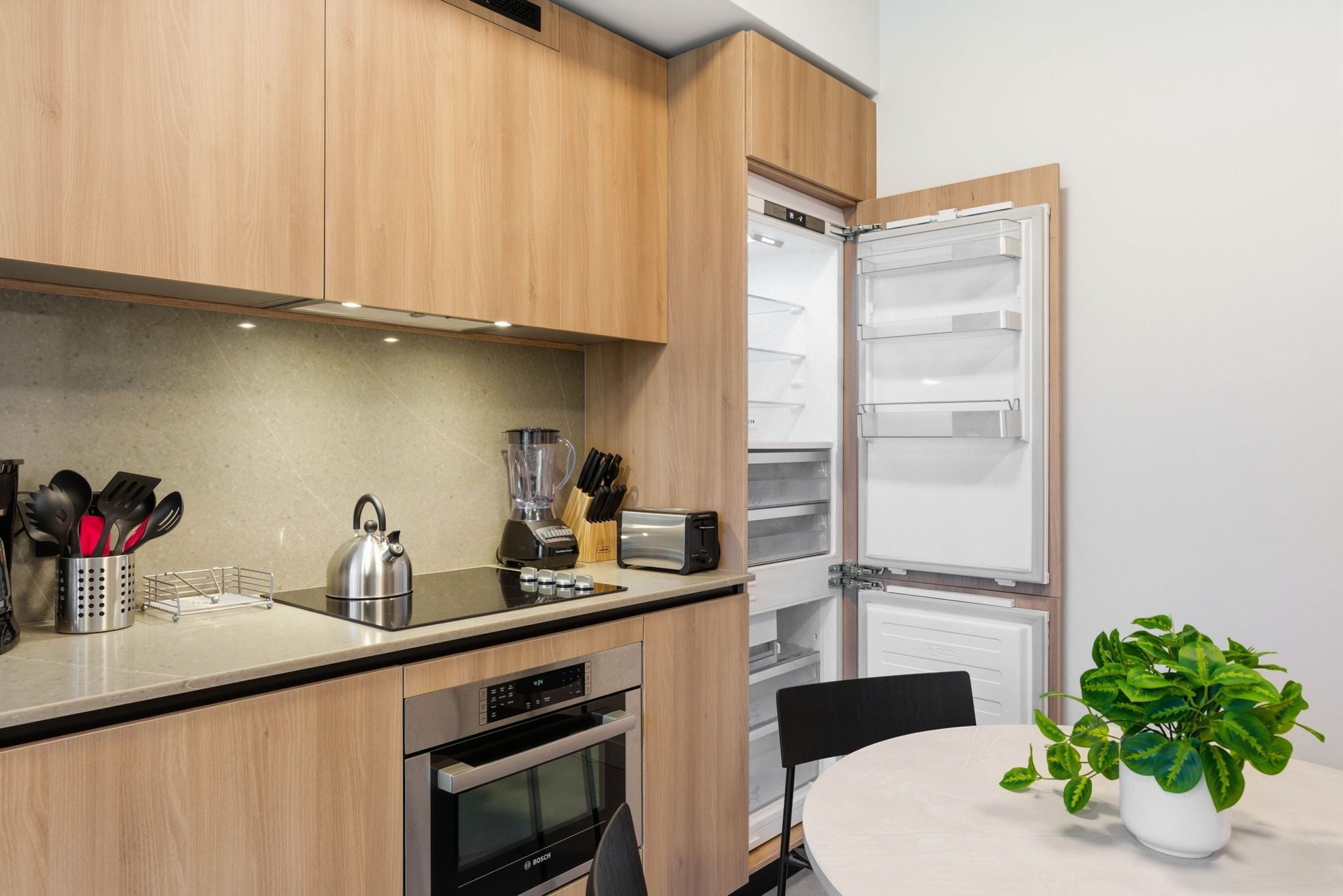 Una cucina moderna con mobili in legno, forno integrato, tostapane e frullatore sul piano di lavoro.