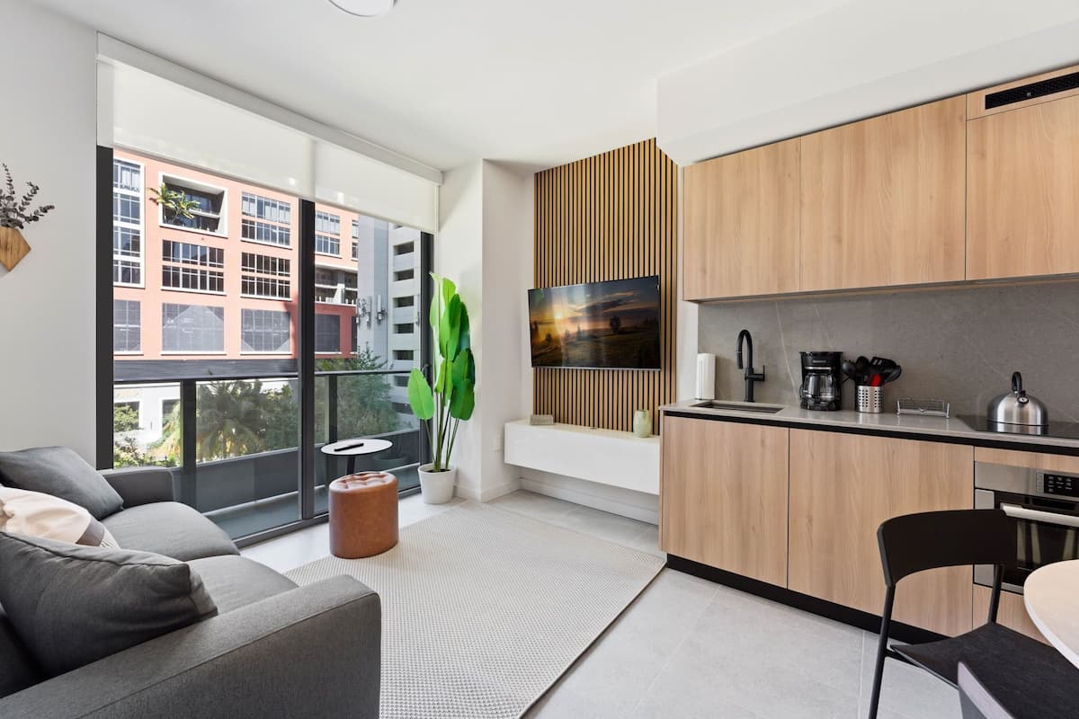 A modern kitchen with wooden cabinets, a built-in oven, and a large window overlooking a cityscape.