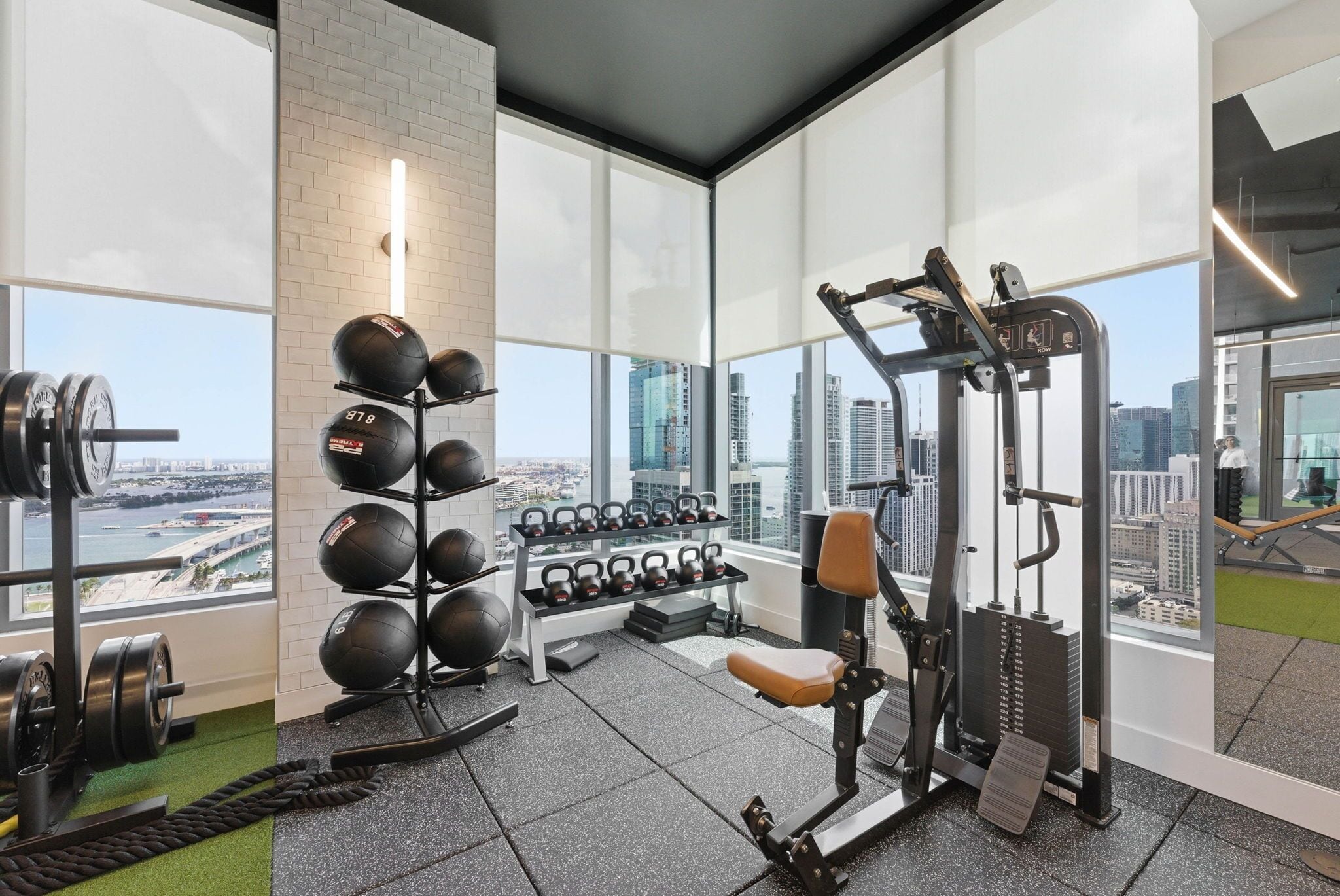 A gym with weightlifting equipment, a bench, and a view of the city.