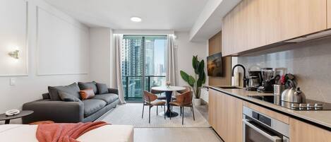 A modern hotel room with a kitchenette, a dining area, and a sofa.