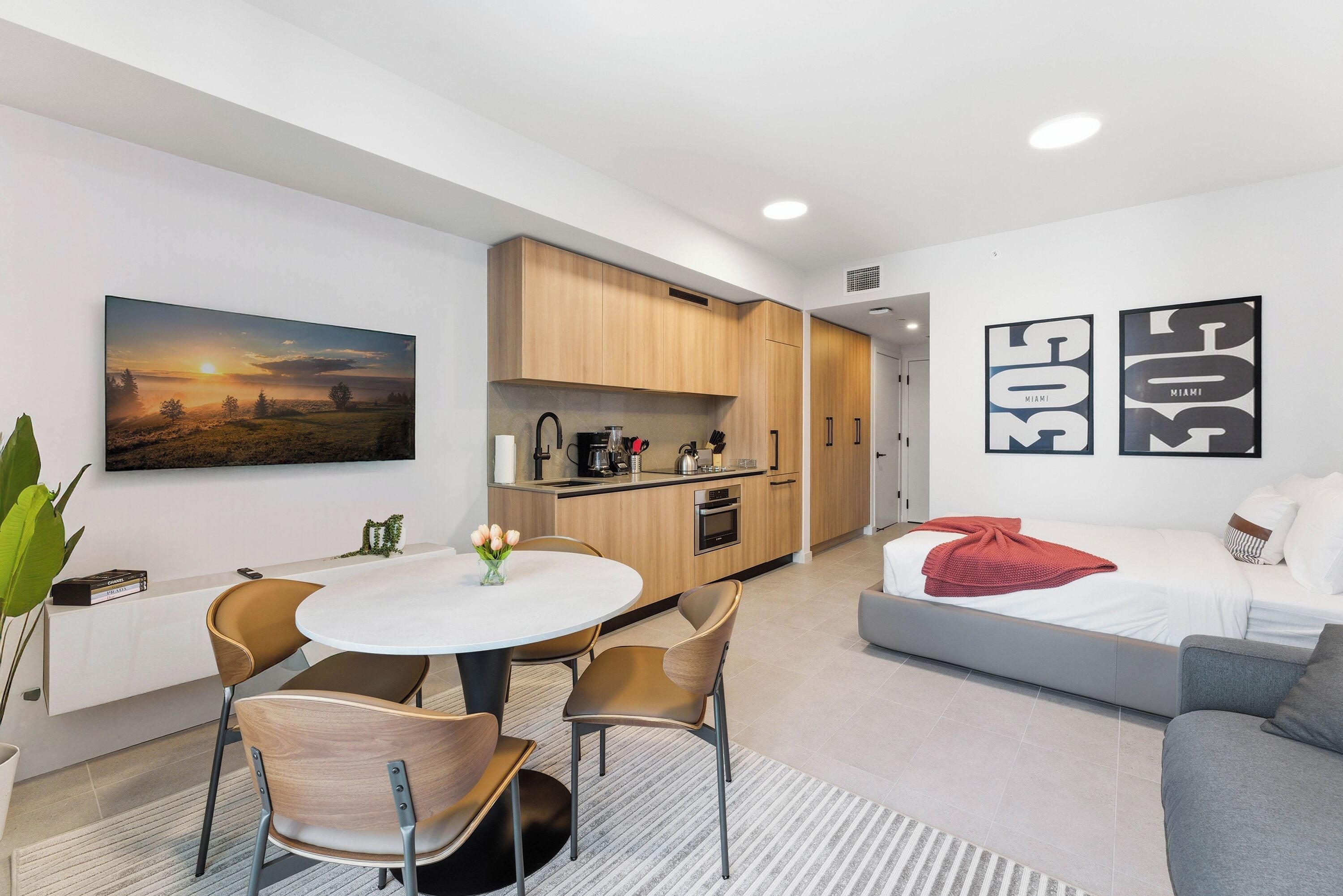 Un espacio habitable moderno y compacto con comedor, kitchenette y cama.