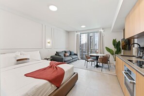 Una habitación de hotel moderna con una cama grande, un sofá, un comedor y una kitchenette.