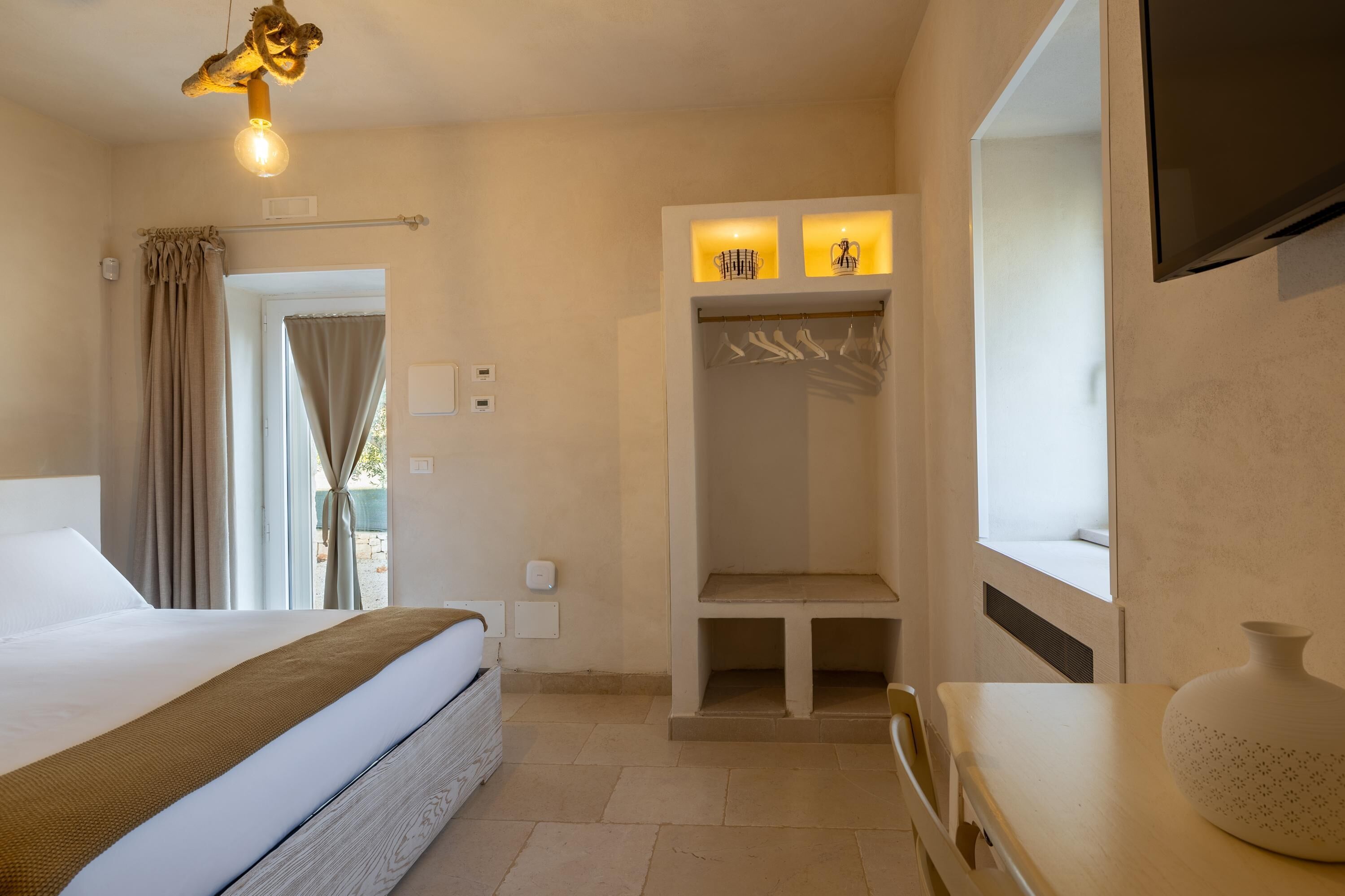 Habitación de hotel con cama, escritorio, silla, armario y televisión.