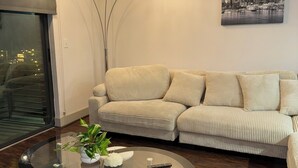En moderne stue med sofa, sofabord i glas og en gulvlampe.