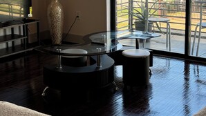En moderne stue med et stort vindue, et rundt glasbord, en sofa og en dekorativ vase.