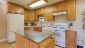 A kitchen with wooden cabinets, a stainless steel island, a refrigerator, a microwave, a dishwasher, and a stove.