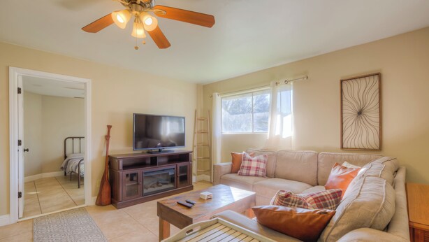 A living room with a television, sofa, coffee table, and a ceiling fan.
