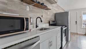 A modern kitchen with a microwave, sink, and refrigerator. - 1BR Condo 1 Block from the Beach & Boardwalk (Wildwood)