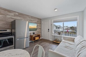 Eine moderne Küche mit Edelstahlgeräten, ein Essbereich mit einem Marmortisch und ein Balkon mit Blick auf Häuser.