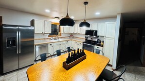 A modern kitchen with stainless steel appliances, white cabinets, and a wooden dining table. - This special place is close to everything, making it easy to plan your visit. (Quitman)