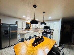 Een moderne keuken met roestvrijstalen apparatuur, witte kasten en een houten eettafel.