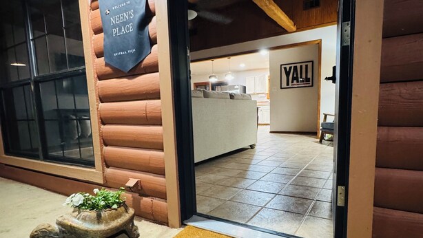 A log cabin entrance with a 'welcome to Neen's Place' sign, a 'hello' mat, and a 'Yall' sign inside. - This special place is close to everything, making it easy to plan your visit. (Quitman)
