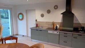 A modern kitchen with grey cabinets, a black range hood, and a window overlooking a garden.