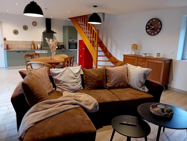 Una sala de estar moderna con un sofá marrón, una mesita de centro y una escalera que sube a un nivel superior.