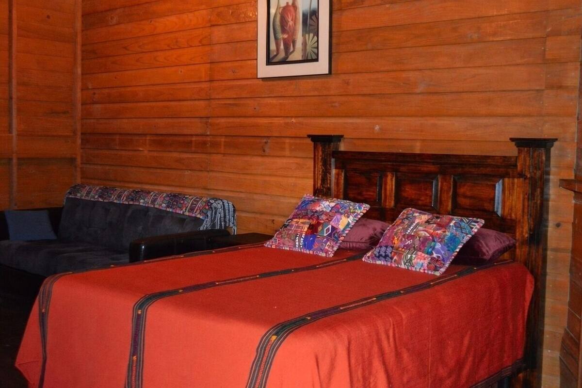 A wooden cabin room with a bed and a couch.