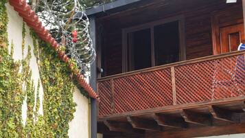A wooden balcony with a lattice railing and a window above it.