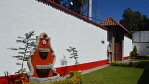 A building with a white exterior, red trim, and a mural of a smiling face. - El Refugio - Hospedaje y Eventos (San Lucas Sacatepequez)