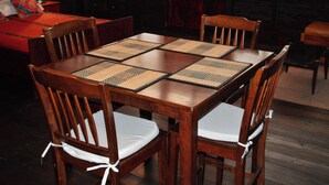A wooden dining table with woven placemats and cushioned chairs. - El Refugio - Hospedaje y Eventos (San Lucas Sacatepequez)