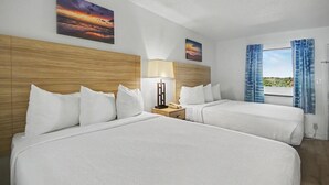 Une chambre d’hôtel avec deux lits, une table de chevet avec une lampe et une fenêtre avec des rideaux.