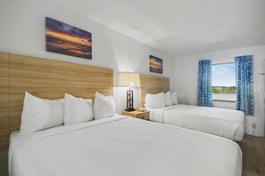 A hotel room with two beds, a nightstand with a lamp, and a window with curtains. - Oceanfront 1BR + Beach Access + Dog Friendly (Myrtle Beach)