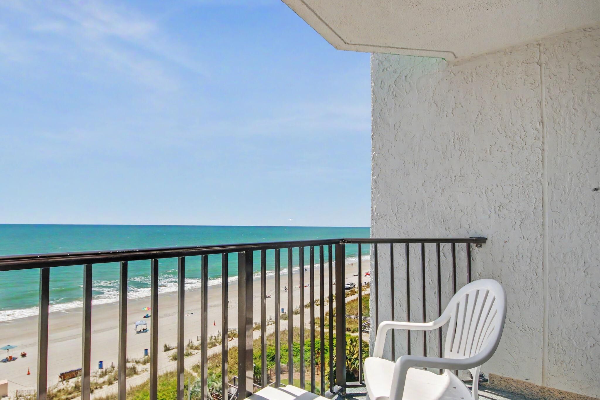 A balcony with a view of a beach and ocean.