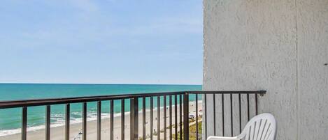 A balcony with a view of a beach and ocean.