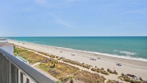 Une plage offrant une vue dégagée sur l’océan, un rivage sablonneux et quelques personnes se prélassant au soleil.