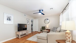 Un salon moderne doté d’un téléviseur à écran plat, d’un ventilateur de plafond, d’un canapé, d’une table basse et d’une lampe.