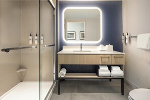 Une salle de bain moderne avec une douche à parois de verre, un meuble-lavabo avec un miroir et des toilettes.