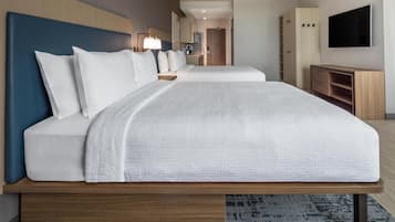 Una habitación de hotel con una cama grande, televisor, escritorio y armario.