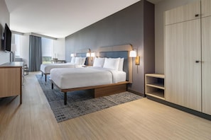 Ein modernes Hotelzimmer mit zwei Betten, einem Schreibtisch, einem Fernseher und einem Kleiderschrank.