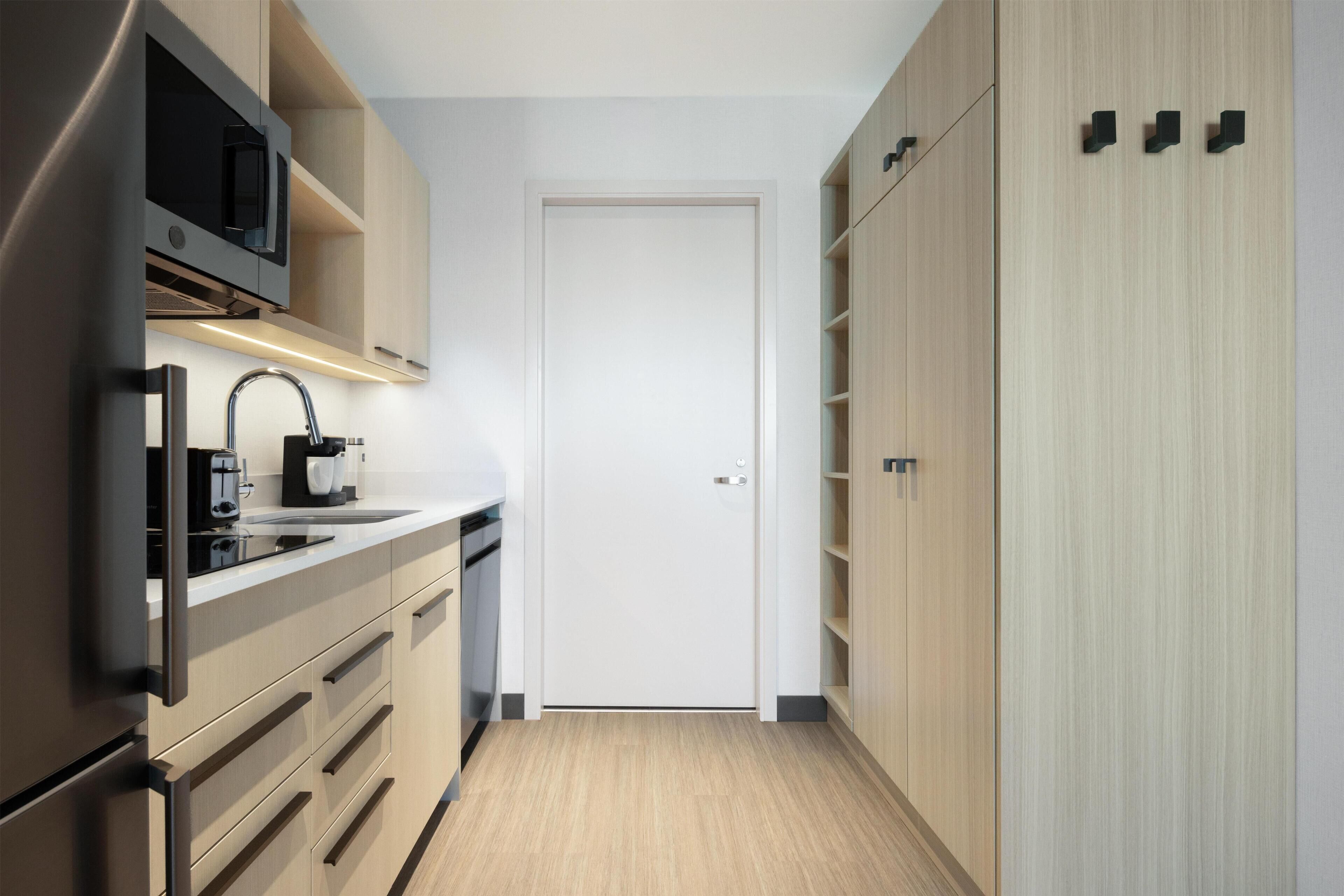 A modern kitchen with a built-in microwave, a coffee maker, and a stainless steel refrigerator.